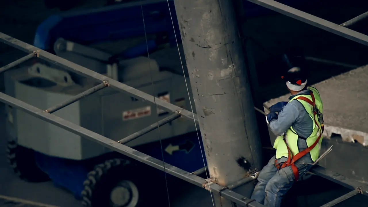 A worker in a safety harness and hi-vis vest working at height